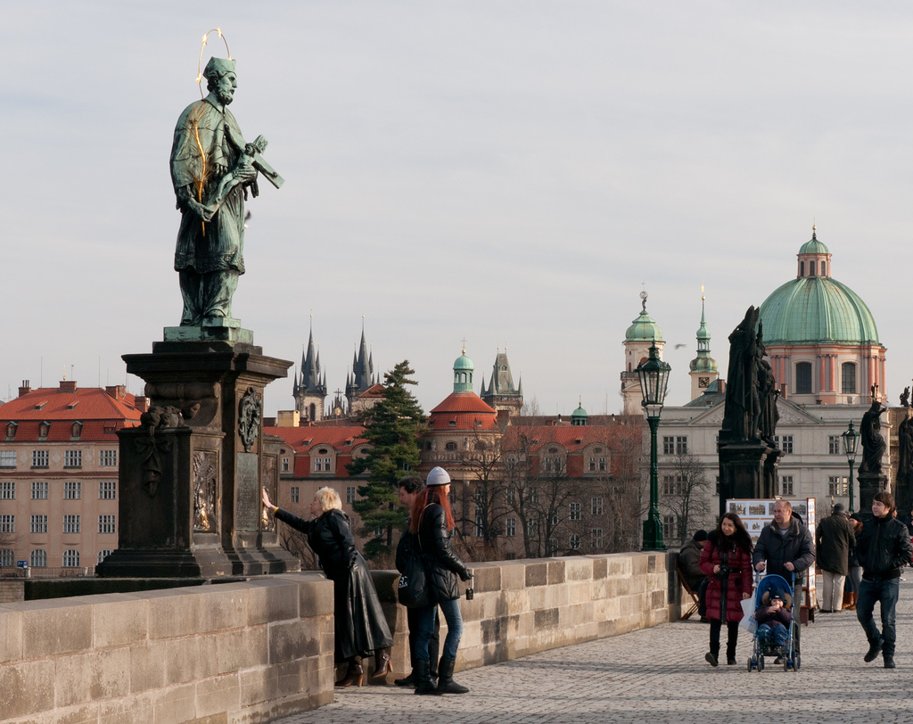 Mujer pidiendo un deseo en la estatua de San Juan Nemopuceno de Praga