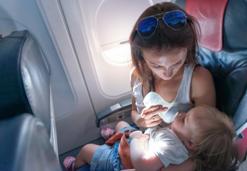 Madre dando de comer a su hijo en el avión