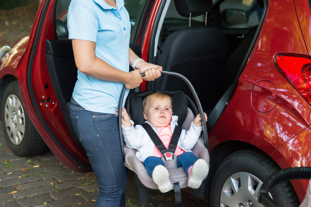 MAdre sacando a su bebé del coche