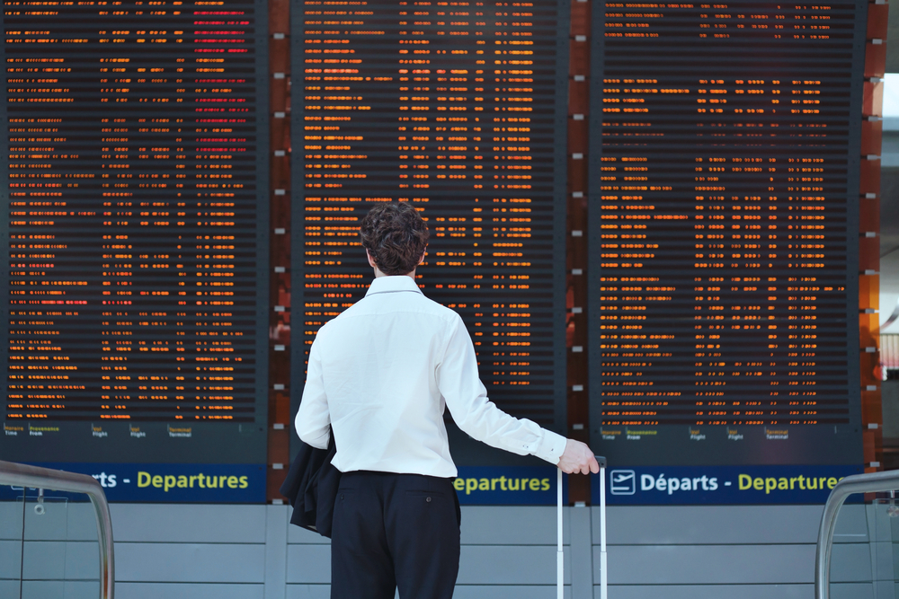 Hombre en el aeropuerto mirando un cartel