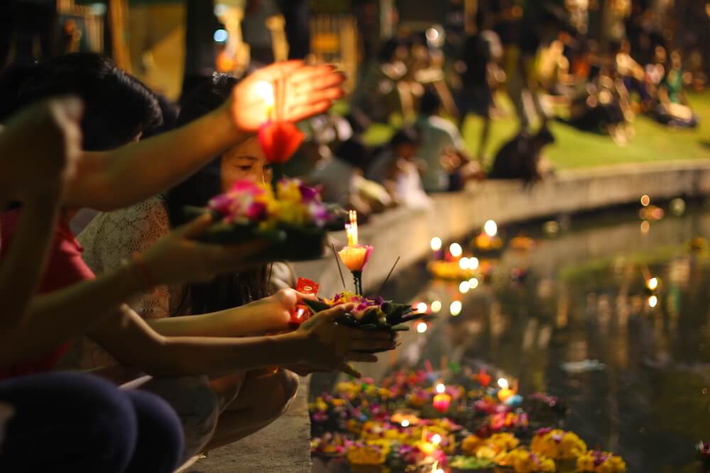 Genta lanzando al agua luces en el Festival Loi Kratong