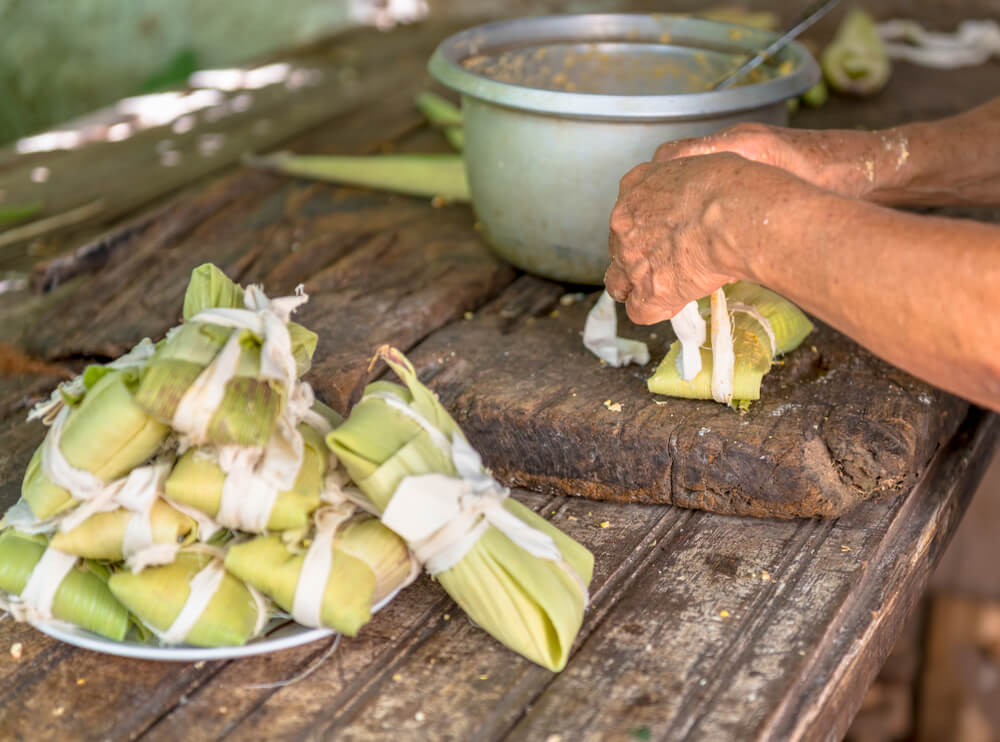 Mujer preparando tamales típicos de la comida cubana