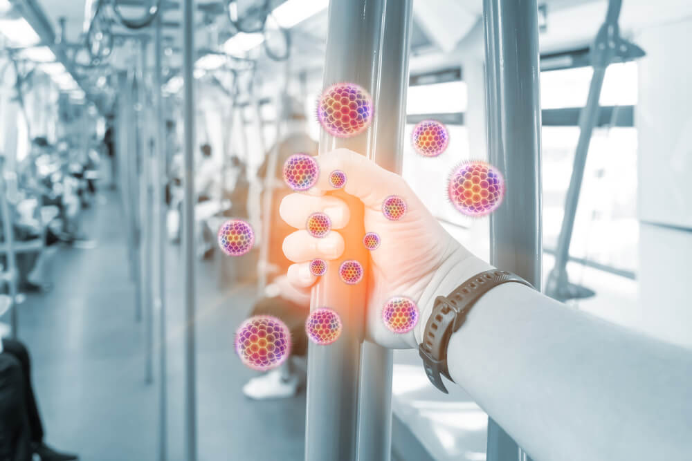 PAsajero en autobús agarrándose a una barra con COVID-19