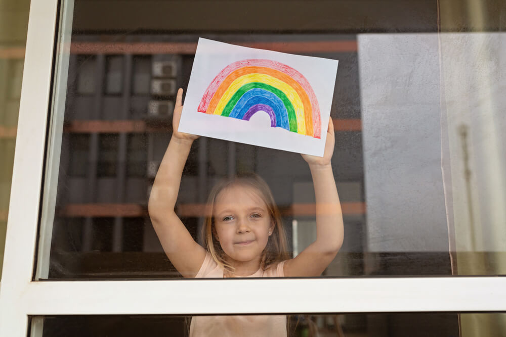 Niña muestra un arcoiris a través de su ventana.
