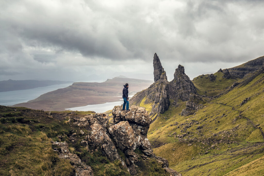 POstal de un turista posando con el Viejo Hombre de Storr de fondo.