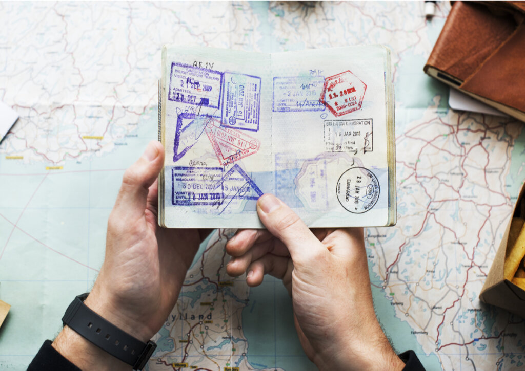 Un pasaporte lleno de sellos en manos de un viajero.