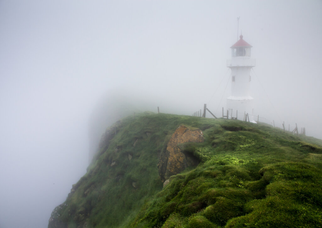 Faro en la costa de una isla con niebla.