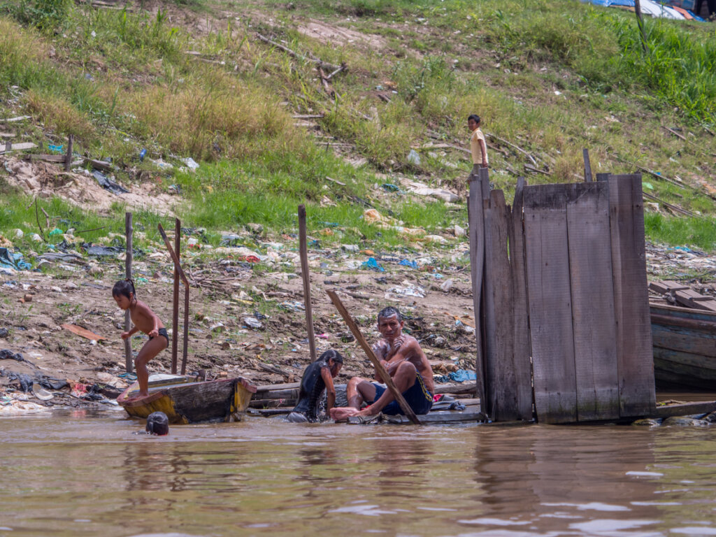 Indígenas tomando un baño a la costa del río.